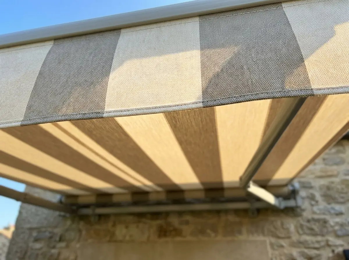 Sunlight glowing through the woven fabric weave and stitched valance of a folding-arm awning canopy